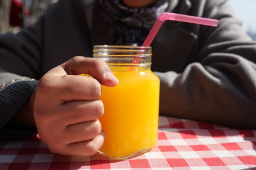 women hand holding a glass of orange juice.