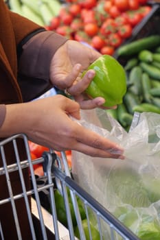 Adding a green pepper to the cart, a natural ingredient for flavorful recipes.