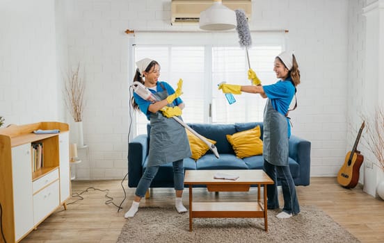 Asian maid joyful cleaning, vacuum as guitar husband playful twist. Singing dancing happily. Music-filled service brings excitement to household chores. Cleaning is fun