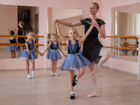 Children's ballet school. Caucasian woman teaching ballet to little girls