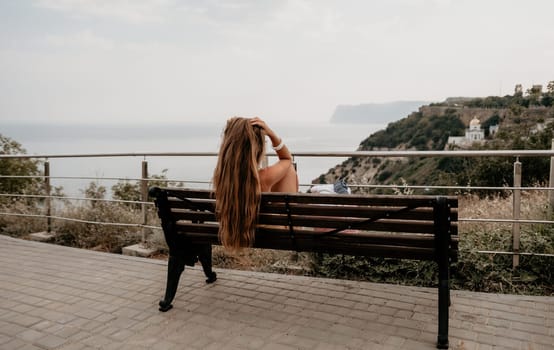 Woman travel sea. Happy tourist taking picture outdoors for memories. Woman traveler looks at the edge of the cliff on the sea bay of mountains, sharing travel adventure journey.