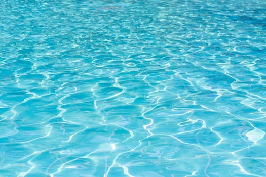 Blue swimming pool water surface and ripple wave background. Summer abstract reflection caustics in swimming pool.