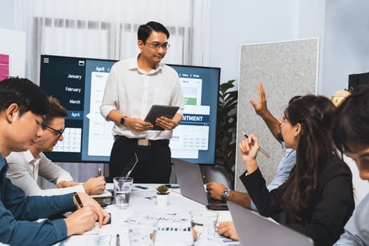 Project manager communicate and collaborate with team using project management software display on monitor, tracking progress of project task and making schedule plan at meeting table. Prudent