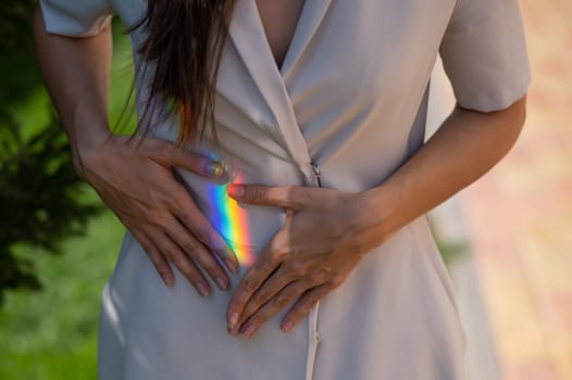 Faceless woman catching rainbow ray with her hands outdoors