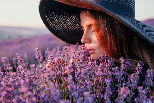 Close up portrait of young beautiful woman in a white dress and a hat is walking in the lavender field and smelling lavender bouquet.