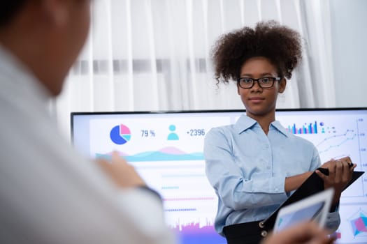 Young african businesswoman presenting data analysis dashboard on TV screen in modern meeting. Business presentation with group of business people in conference room. Concord