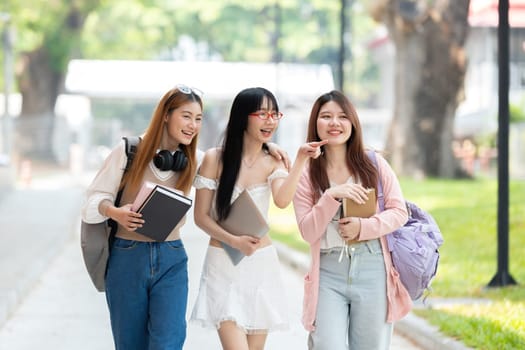 Happy Asian teenager female college student holding book and looking at nature outdoors at university Prepare for class.