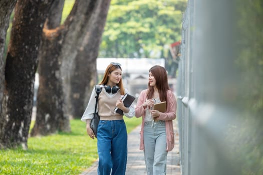 Two female student friends were chatting while walking to a classroom on campus..