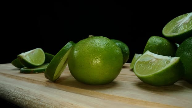 Close-up, a vibrant slice of fresh lime rests upon a rustic wooden cutting board, exuding freshness and vitality. The translucent membranes of the green lime slice placed on cutting board. Comestible.