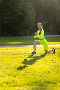 A woman in a neon yellow outfit is doing a yoga pose on a grassy field. The bright colors of her outfit and the green grass create a cheerful and energetic atmosphere