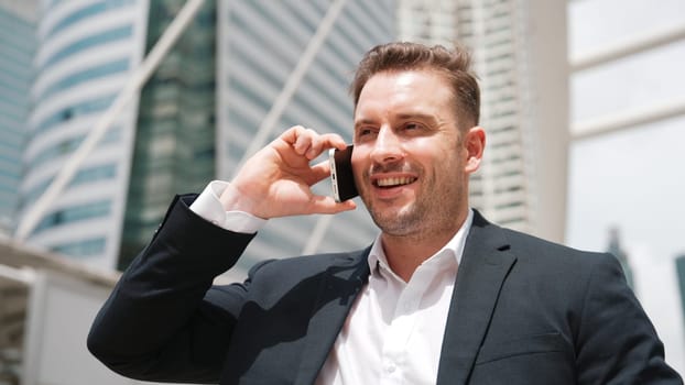 Smart caucasian businessman calling his colleague to plan financial strategy while standing at urban city. Project manager using his mobile phone to communicate with marketing team. Lifestyle. Urbane.