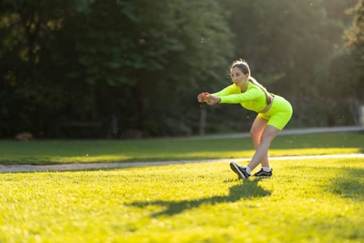 A woman in a neon yellow outfit is stretching on a grassy field. The bright colors of her outfit and the green grass create a cheerful and energetic mood