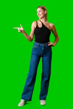 Young Woman Pointing at Something against green background in studio