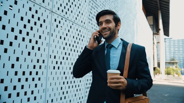 Smart business man using phone to talking about business investment. Happy manager walking at street while talking on smart phone to discuss business plan or marketing strategy or working. Exultant.