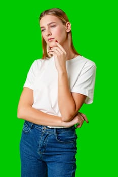 Woman Standing With Hand on Chin on green background in studio