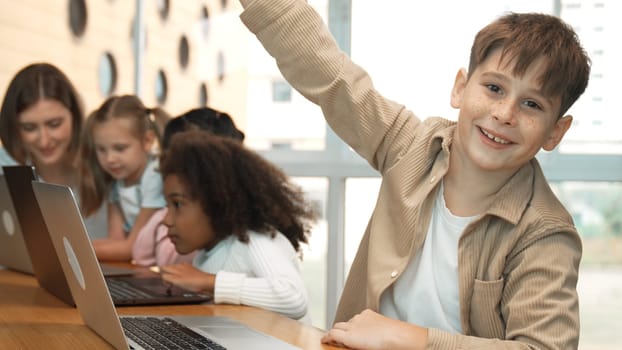 Boy raised hand while multicultural friend learning prompt at STEM technology class. Diverse student study about engineering code and programing system. Answer question. asking, voting. Erudition.