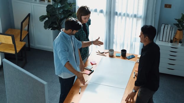 Top view of smart business team explain and discuss about plan at meeting table with sticky notes. Group of diverse people brainstorming idea at boardroom while standing at meeting table. Convocation.