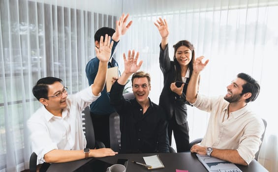 Group of diverse office worker join hand together in office room symbolize business synergy and strong productive teamwork in workplace. Cooperation and unity between business employee. Prudent