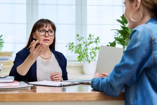 Female psychologist therapist working with young teen girl sitting in office. Teenage female student at therapy meeting with counselor. Psychology therapy psychotherapy youth mental health treatment