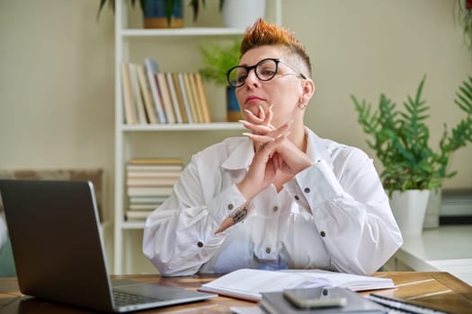 Portrait of mature businesswoman working at home on computer laptop. Serious middle-aged female in glasses looking at pc screen. Remote business work career management marketing