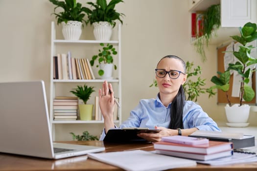 Woman psychologist mental therapist counselor social worker working remotely using computer for online therapy meeting. Female with clipboard look talk at laptop. Technology psychology psychotherapy