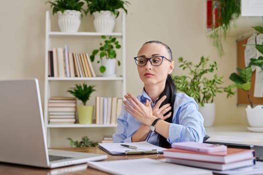 Woman psychologist mental therapist counselor social worker work remotely using computer for online therapy session. Female with clipboard looking at laptop, showing psychological gestures to patient