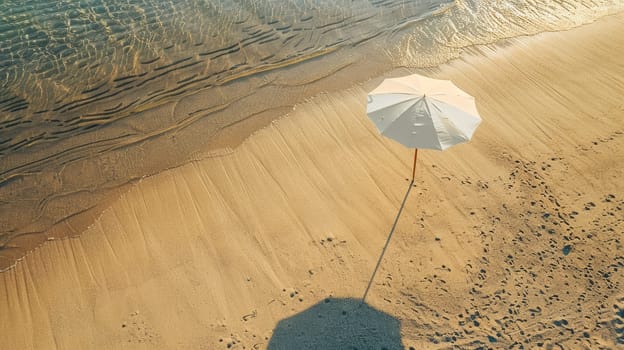 An umbrella rests on the sandy shore of the beach, overlooking the vast expanse of water. Travelers enjoy the scenic landscape as they relax on the shore AIG50