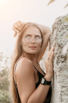 Woman travel sea. Young Happy woman in a long red dress posing on a beach near the sea on background of volcanic rocks, like in Iceland, sharing travel adventure journey