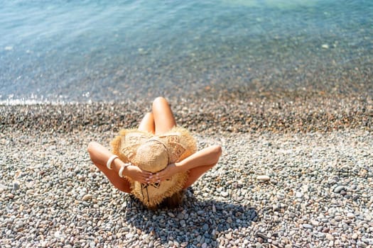 Beach Relaxation woman lies on a pebble beach, legs raised, and arms spread out. The concept of travel, vacation at sea.