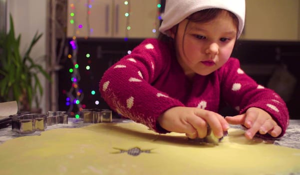 Little girl carves Christmas cookies. French text on a sweater - falls