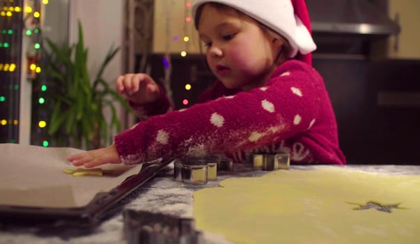 Little girl carves Christmas cookies. French text on a sweater - falls