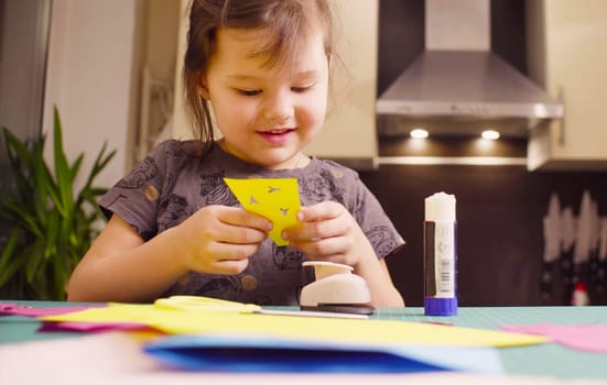 Scrapbooking. Little girl doing a postcard. She is cutting birds from a paper. Children's creativity, handicraft