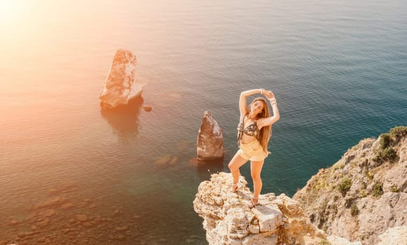 Woman travel sea. Happy tourist taking picture outdoors for memories. Woman traveler looks at the edge of the cliff on the sea bay of mountains, sharing travel adventure journey.