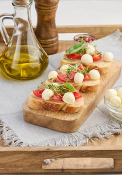 Round mozzarella, cherry tomatoes and microgreens on a piece of white bread, a healthy sandwich, top view