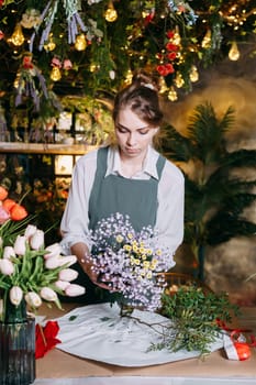 A woman in her florist shop collects bouquets of flowers. The concept of a small business. Bouquets of tulips for the holiday on March 8