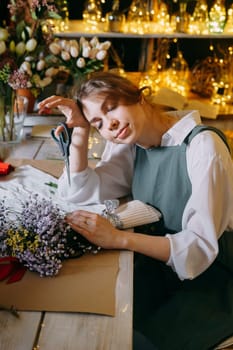 A woman in her florist shop collects bouquets of flowers. The concept of a small business. Bouquets of tulips for the holiday on March 8