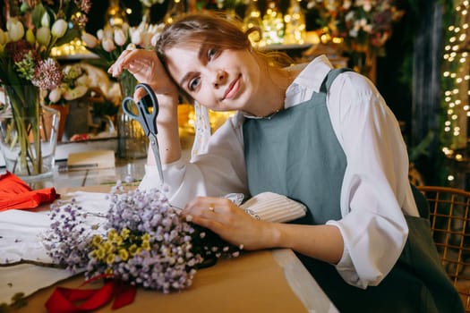 A woman in her florist shop collects bouquets of flowers. The concept of a small business. Bouquets of tulips for the holiday on March 8