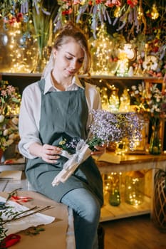 A woman in her florist shop collects bouquets of flowers. The concept of a small business. Bouquets of tulips for the holiday on March 8