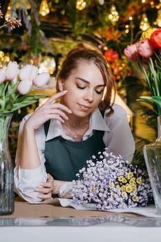 A woman in her florist shop collects bouquets of flowers. The concept of a small business. Bouquets of tulips for the holiday on March 8