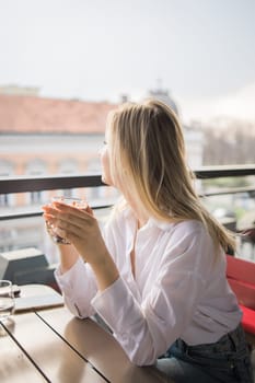 Gen z blonde woman drinks hot chocolate in summer cafe. Tasty beverage and break