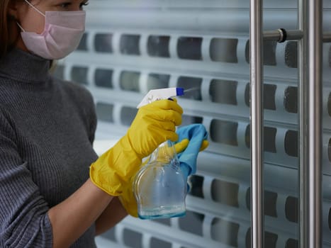 Cleaner cleans the handrail by spraying a cleaning agent to kill viruses for hygiene, put on rubber gloves and wipes.