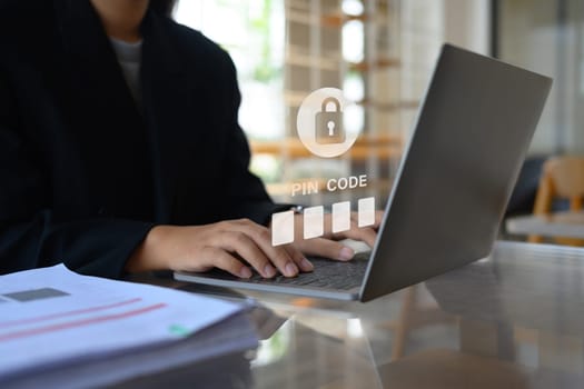 Businesswoman in black suit hands entering pin code on laptop. Cybersecurity concept.