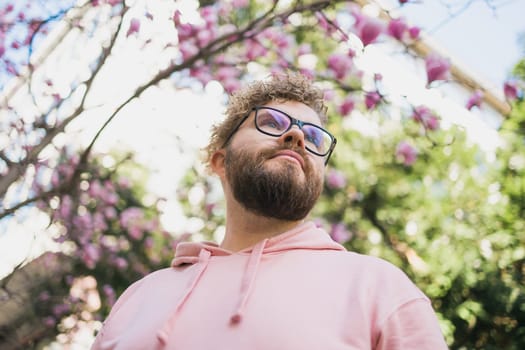 Springtime concept. Bearded man on background bloom of magnolia. Spring beauty season. Botany and nature. Happy spring concept. Hipster guy enjoy blossom aroma.