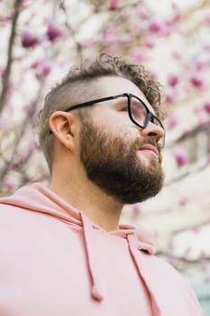 Springtime concept. Bearded man on background bloom of magnolia. Spring beauty season. Botany and nature. Happy spring concept. Hipster guy enjoy blossom aroma.