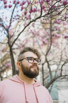Springtime concept. Bearded man on background bloom of magnolia. Spring beauty season. Botany and nature. Happy spring concept. Hipster guy enjoy blossom aroma.