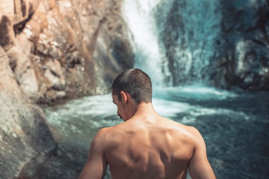 Summer background back shot of a male in front of crystal clear waterfalls. High quality photo