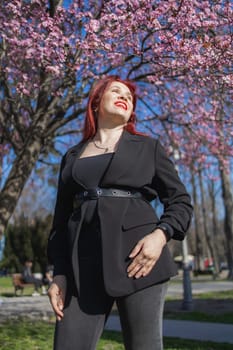 Woman with cherry flowers surrounded by blossoming trees copy space. Beauty and seasonal change and spring bloom season concept