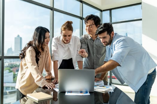 Asian project manager uses laptop displayed data analysis while professional business team brainstorming marketing idea at business meeting. Working together,sharing idea, planing strategy. Tracery.