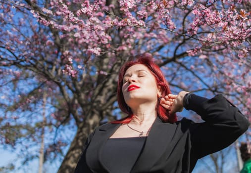 Woman with cherry flowers surrounded by blossoming trees copy space. Beauty and seasonal change and spring bloom season concept