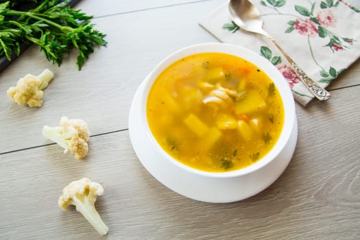 Homemade chicken vegetable soup on rustic wooden background .